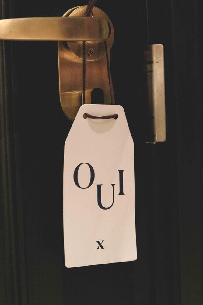 Hoxton Paris - white door hanger saying oui