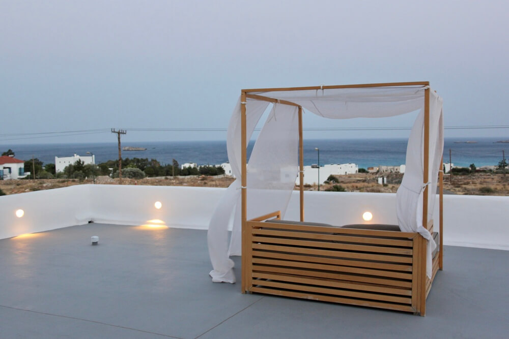 A wooden cabana with white drapes overlooking the bay