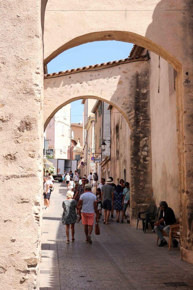 St Tropez - people walking down the street with stone arches overhead