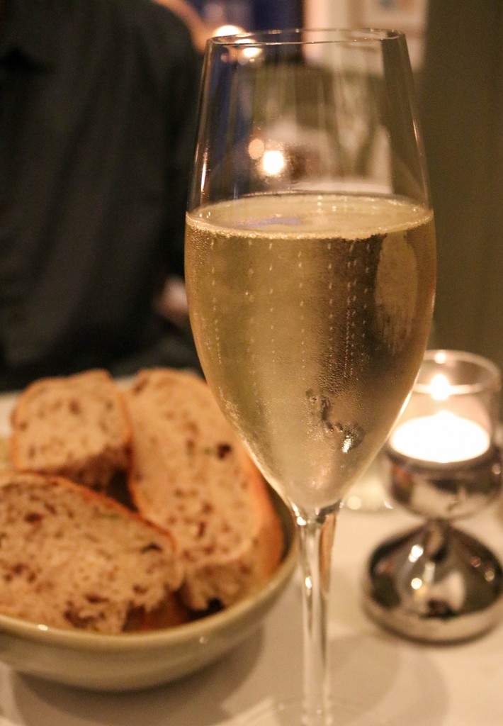 Alba Restaurant Review - an elegant glass of white wine, with bowl of brown bread in background